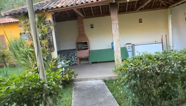 Chalé vermelho com varanda e jardim florido no sítio