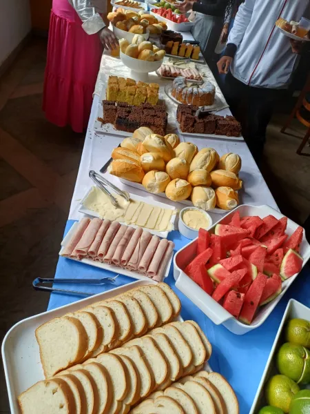 Mesa farta com pães, bolos, frutas e queijos servida aos grupos