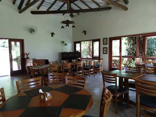 Gramado amplo com quiosques e tenda, cercado de mata