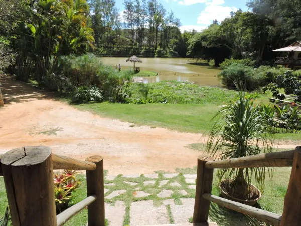 Gramado com balanço, mesas de piquenique e chalé amarelo