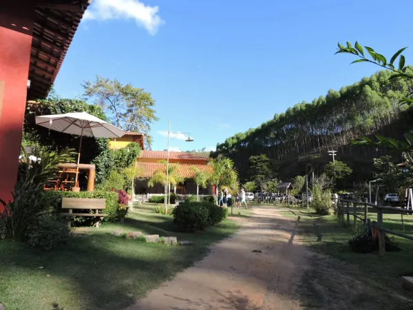 Caminho de terra entre chalés, jardins e mata preservada