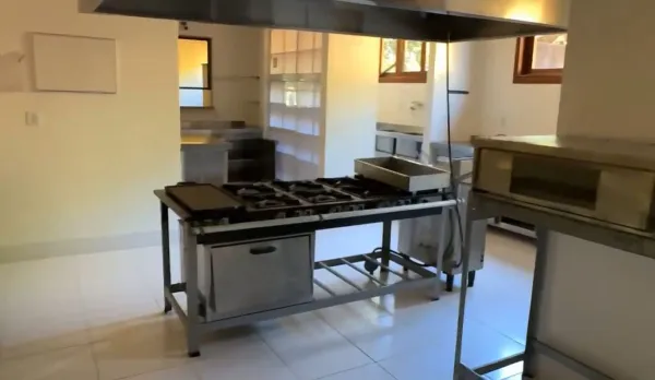 Quiosque coberto com churrasqueira cercado de plantas