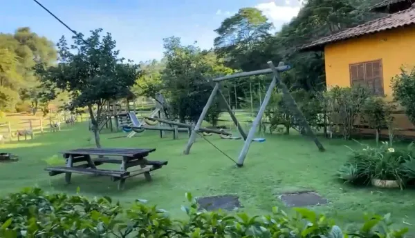 Área de recreação com balanços de madeira e mesas de piquenique